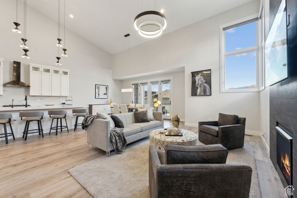 Living area featuring light wood-type flooring, high vaulted ceiling, a fireplace, and baseboards