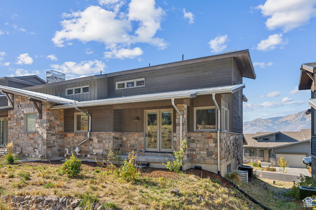 View of front of property featuring stone siding, covered porch, board and batten siding, and a mountain view