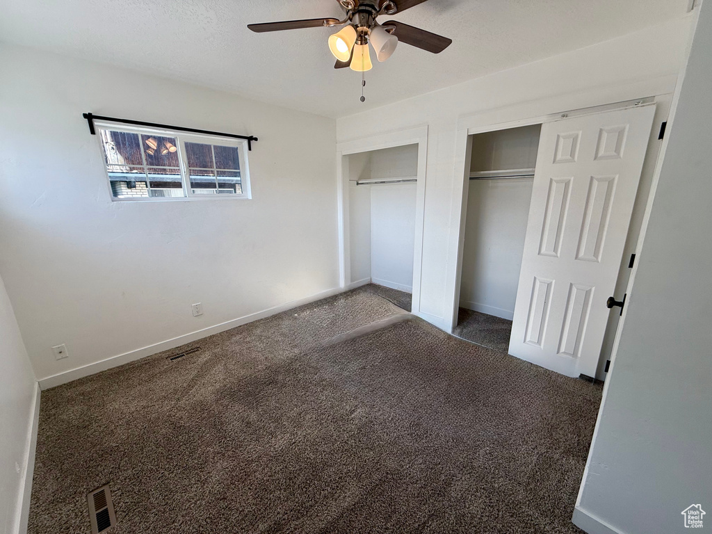 Unfurnished bedroom with two closets, carpet floors, baseboards, and a ceiling fan