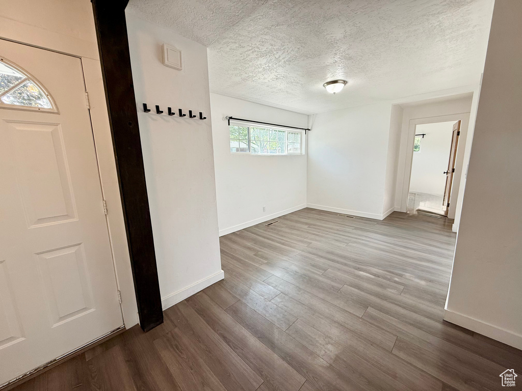 Entrance foyer featuring a textured ceiling, baseboards, and dark wood-type flooring