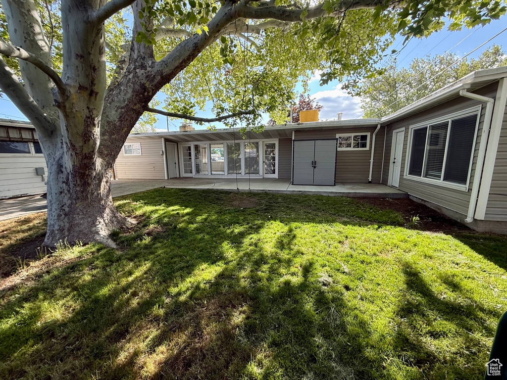 Back of house with a patio area, a yard, and a chimney