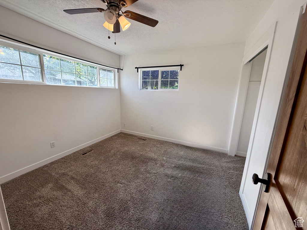 Unfurnished bedroom with carpet flooring, a textured ceiling, baseboards, and a ceiling fan