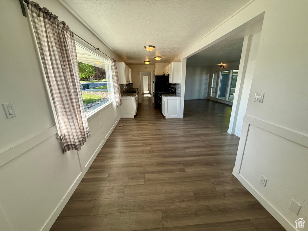 Hall featuring a textured ceiling, dark wood-type flooring, and baseboards