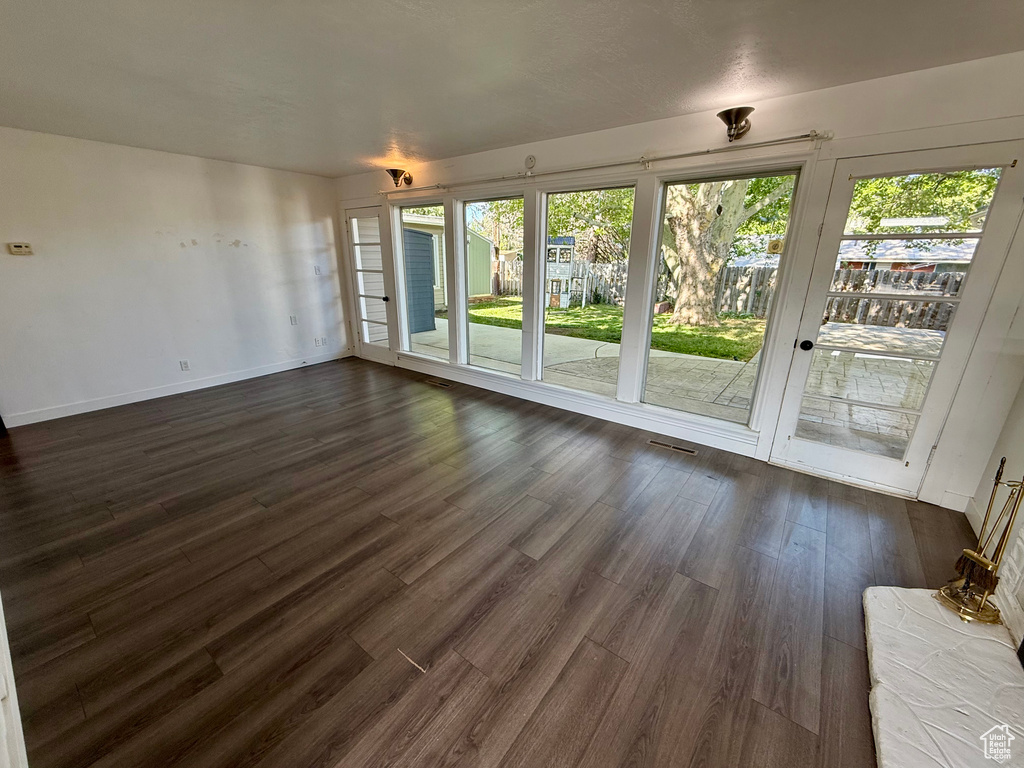Unfurnished living room with dark wood-style floors and baseboards