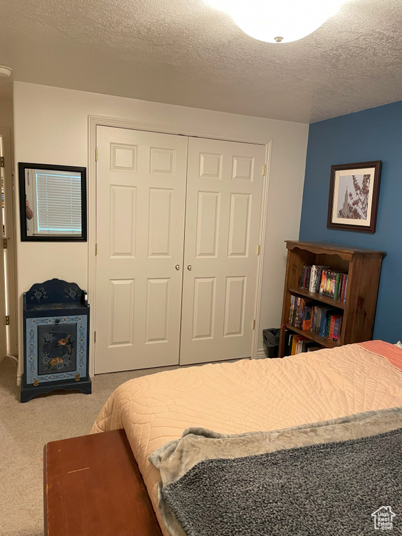 Bedroom with carpet, a closet, and a textured ceiling