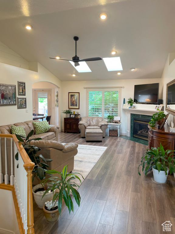 Living room with a premium fireplace, a skylight, healthy amount of natural light, arched walkways, and recessed lighting