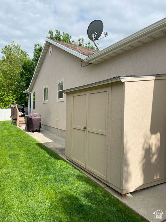 View of property exterior with stucco siding, a lawn, and a deck