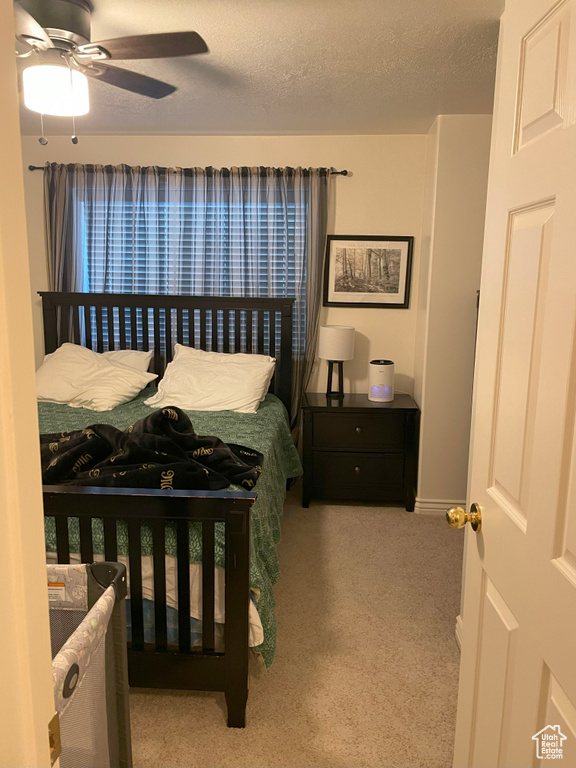 Bedroom featuring carpet floors, a textured ceiling, a ceiling fan, and baseboards
