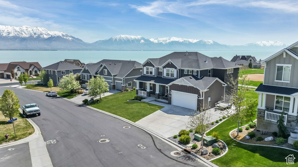 View of front facade featuring board and batten siding, driveway, a residential view, and a water and mountain view