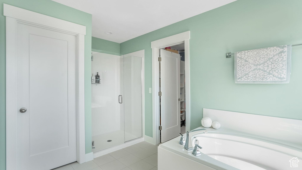 Bathroom with a shower stall, a bath, tile patterned flooring, and baseboards
