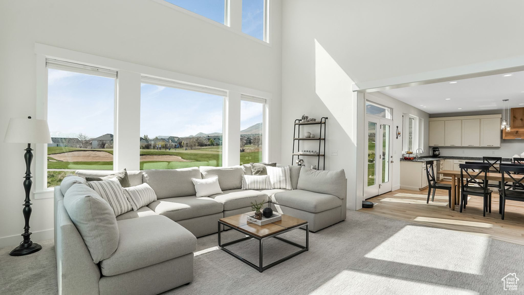 Living area featuring healthy amount of natural light, a high ceiling, light wood finished floors, and recessed lighting