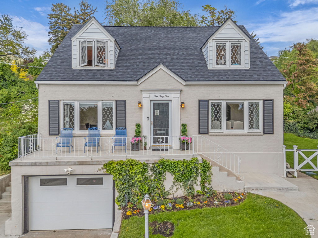 New england style home with a garage and roof with shingles