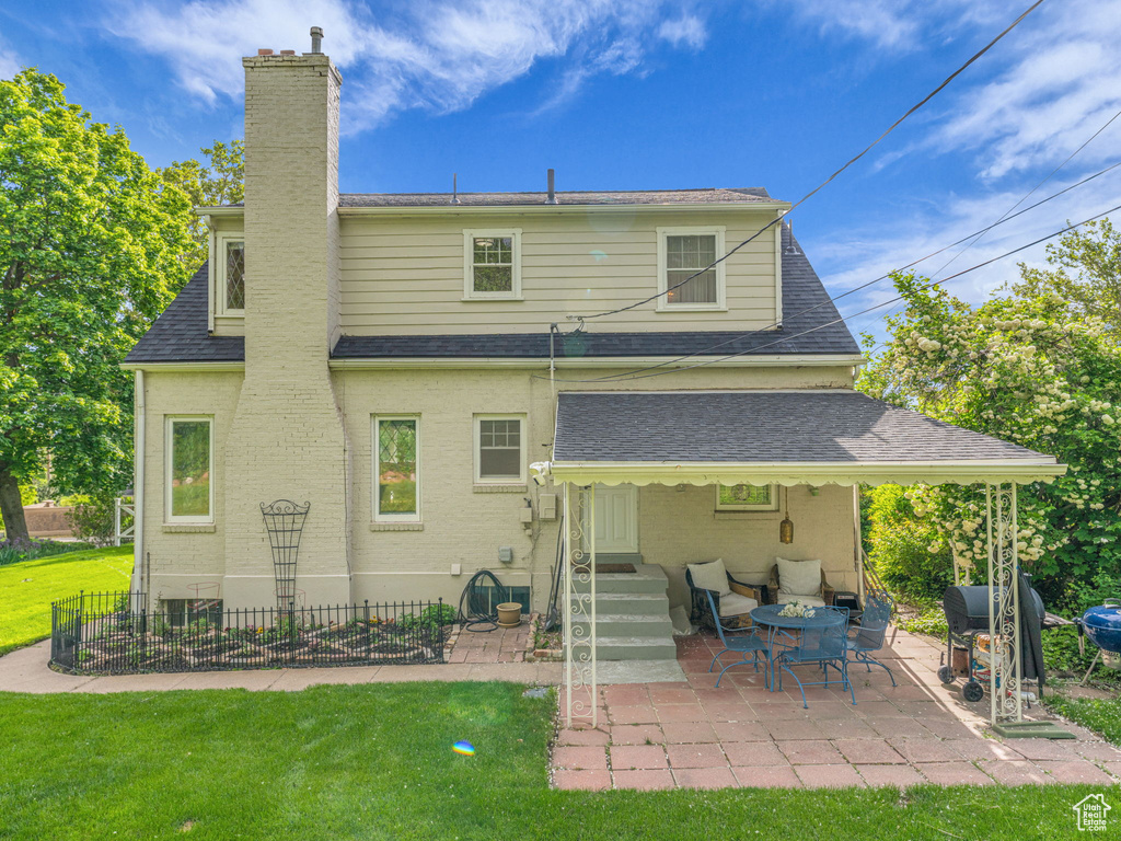 Rear view of property with a patio area, a shingled roof, a chimney, and brick siding