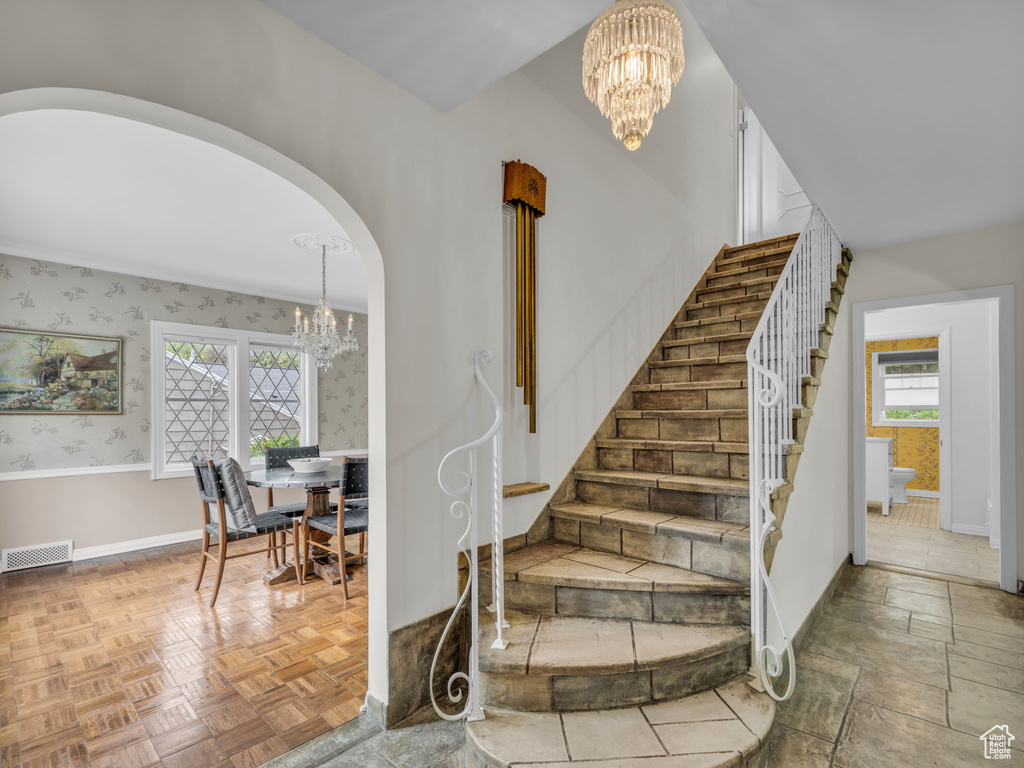 Staircase with a chandelier, baseboards, and arched walkways