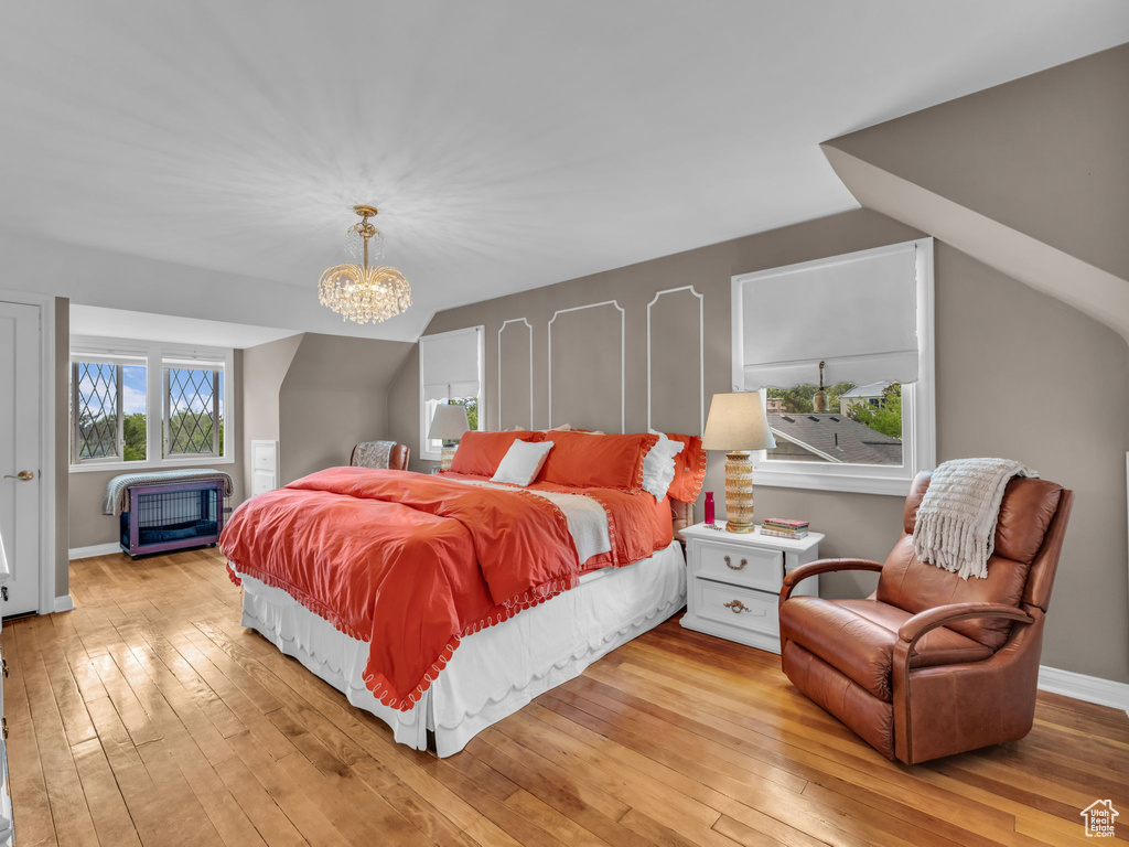 Bedroom featuring light wood-style flooring, a chandelier, baseboards, and lofted ceiling
