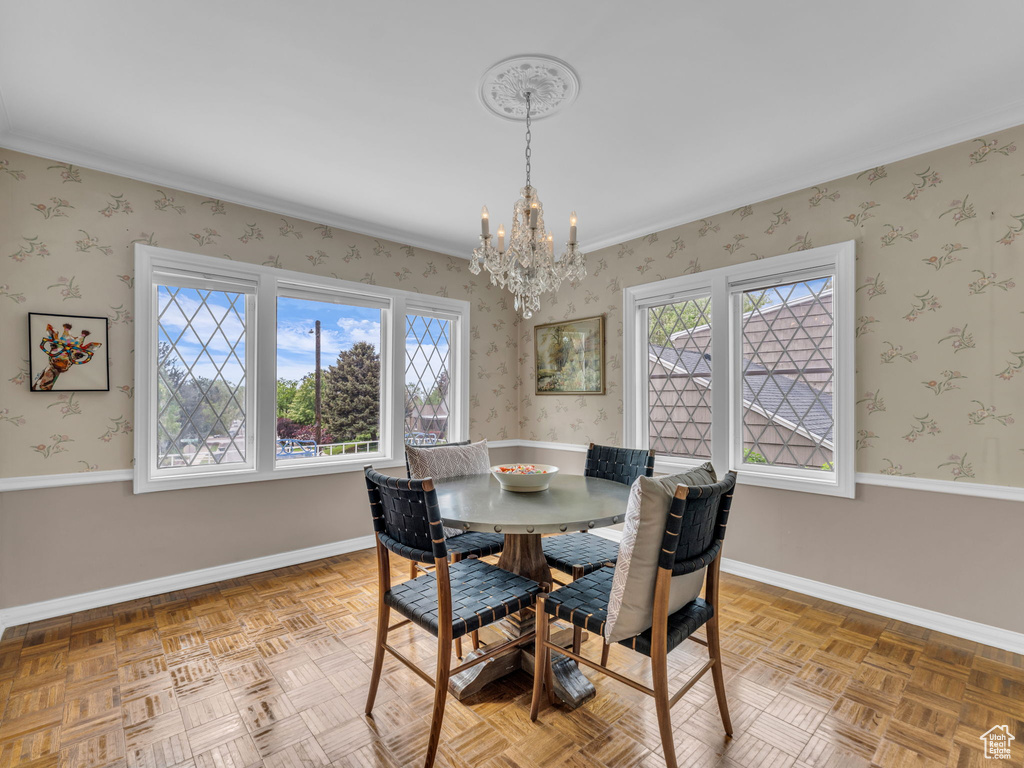 Dining space featuring a chandelier, plenty of natural light, wallpapered walls, baseboards, and crown molding