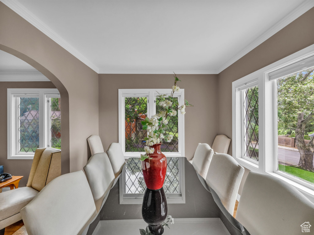 Dining space featuring arched walkways, ornamental molding, and healthy amount of natural light