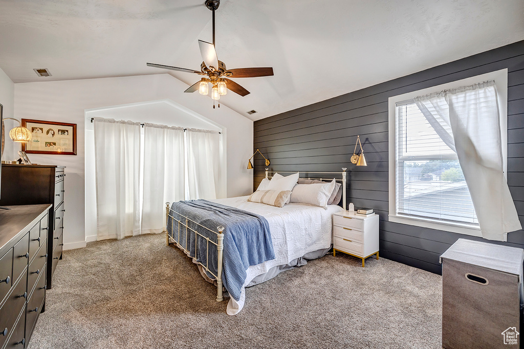 Bedroom with lofted ceiling, carpet flooring, a ceiling fan, and wood walls
