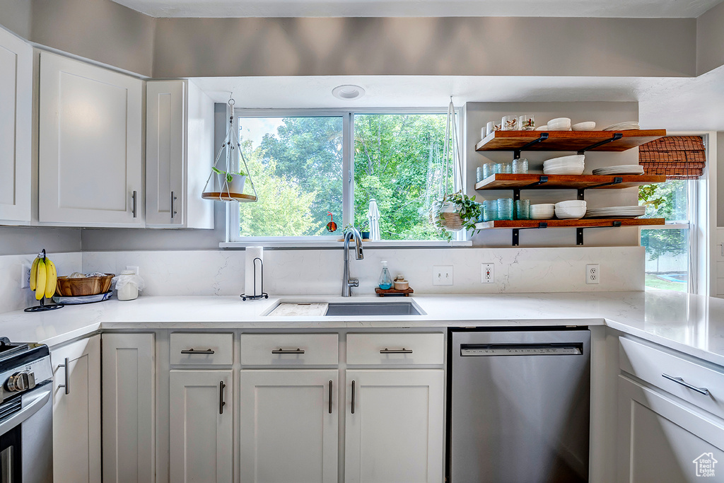 Kitchen featuring stainless steel appliances, a sink, open shelves, and plenty of natural light