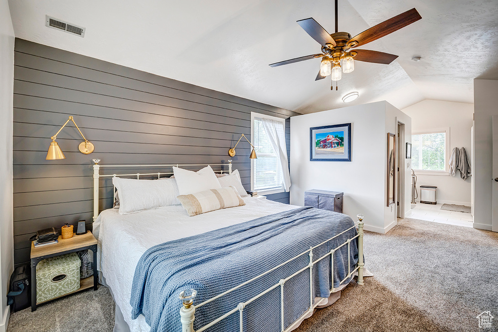 Bedroom featuring vaulted ceiling, carpet, baseboards, wood walls, and ceiling fan
