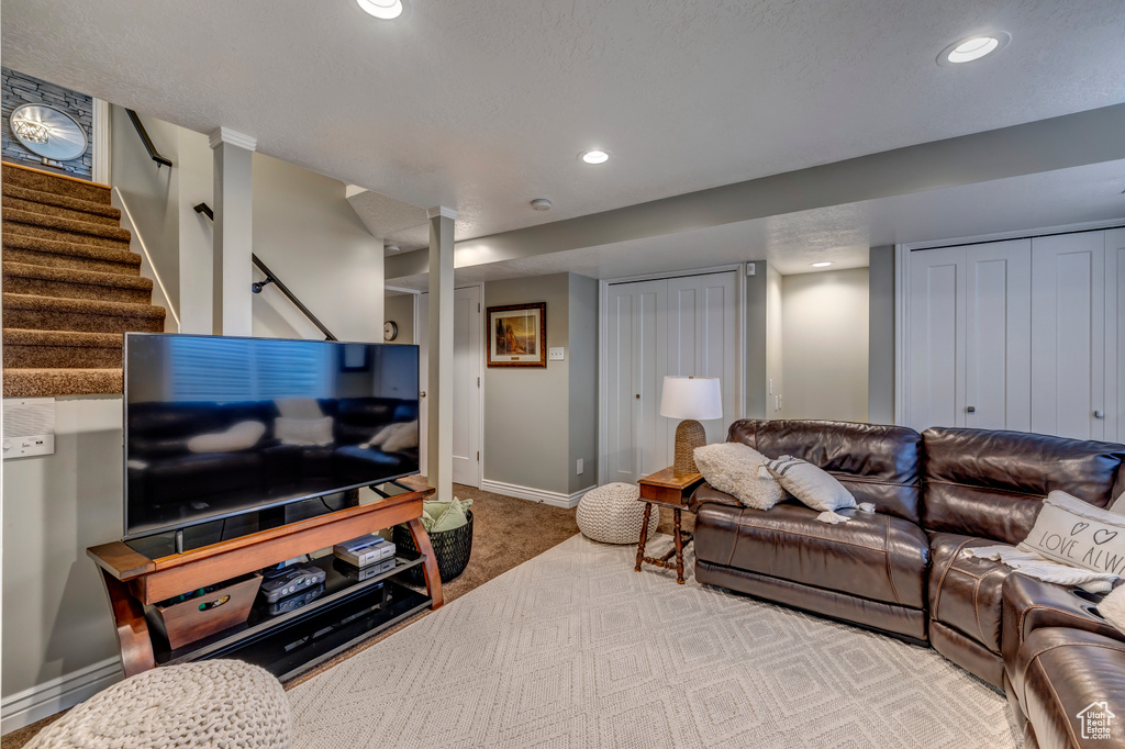 Carpeted living room featuring baseboards, recessed lighting, and stairway