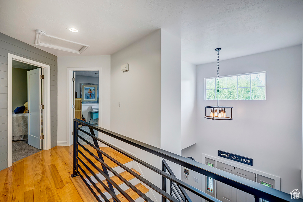 Hall with an upstairs landing, a chandelier, light wood-style floors, recessed lighting, and baseboards