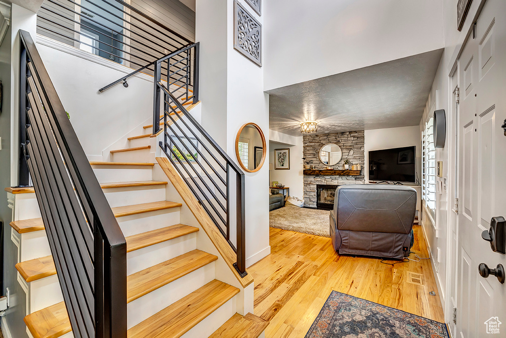 Entrance foyer with wood finished floors, stairs, and a fireplace