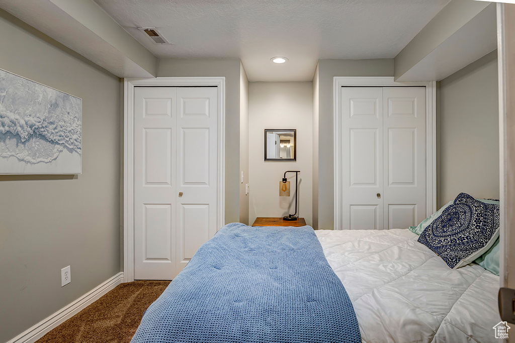 Bedroom featuring multiple closets, dark carpet, baseboards, and recessed lighting