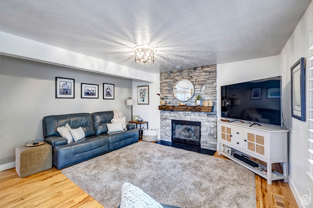 Living area with wood finished floors, a fireplace, baseboards, and a textured ceiling