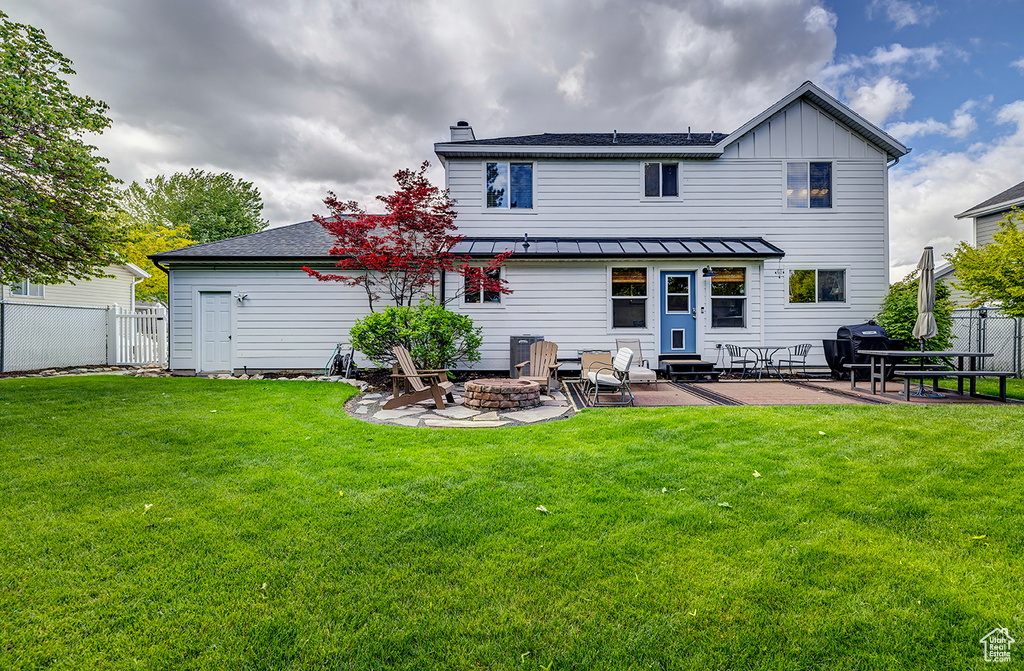 Back of property featuring entry steps, a patio area, a fire pit, a chimney, and a standing seam roof
