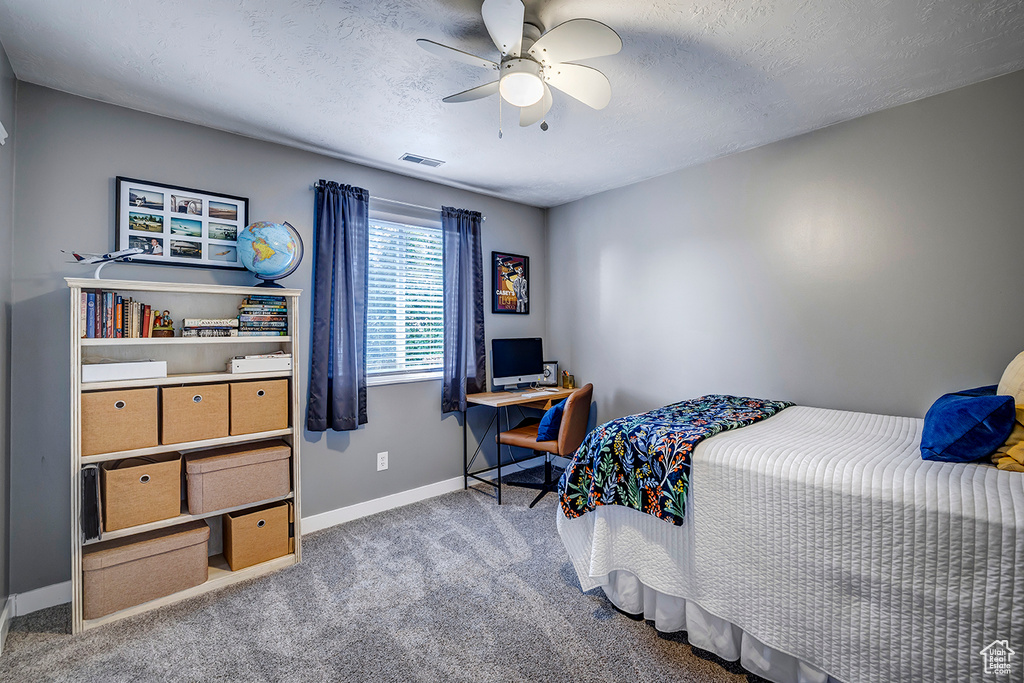 Carpeted bedroom featuring baseboards, a ceiling fan, an office area, and a textured ceiling