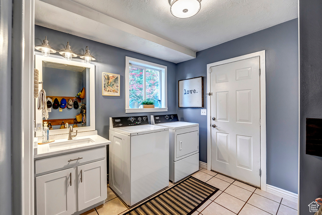 Washroom featuring washer and dryer, light tile patterned floors, baseboards, and a sink