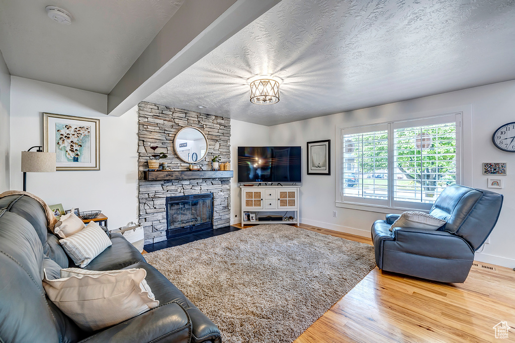Living room featuring wood finished floors, a fireplace, baseboards, and a textured ceiling