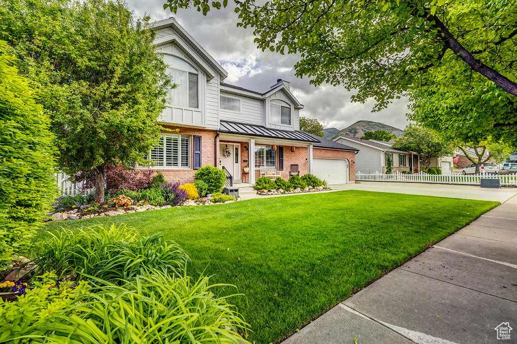 View of front of property with brick siding, concrete driveway, a garage, and a standing seam roof