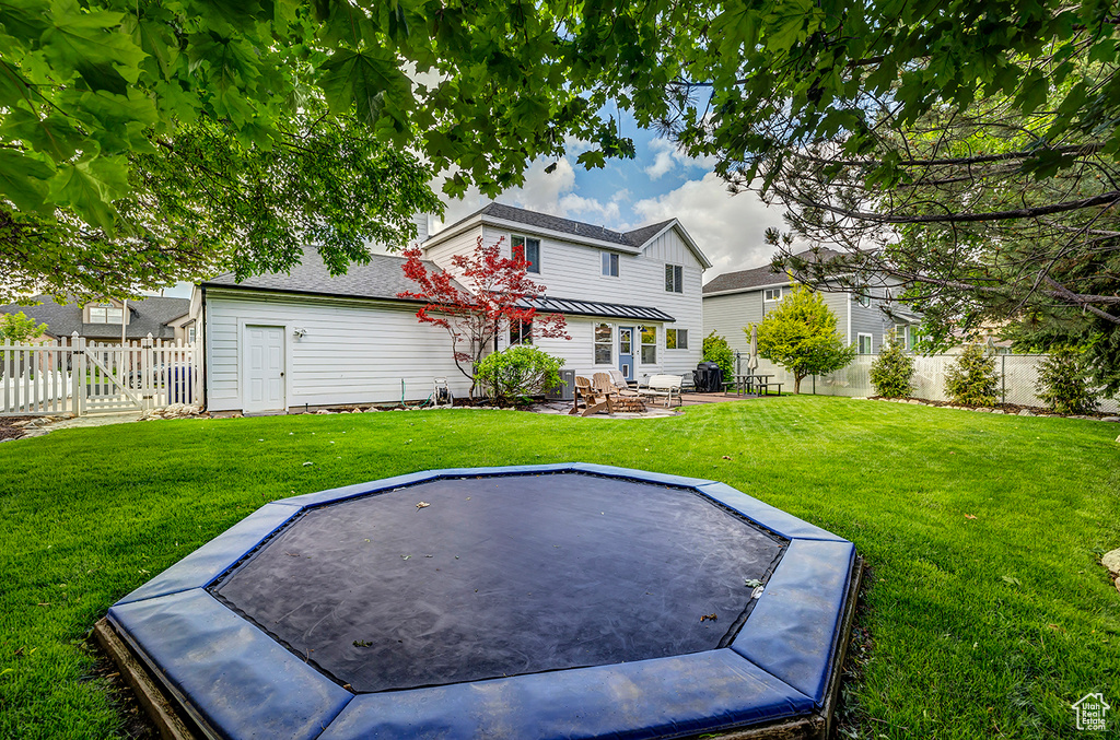 Rear view of house with a trampoline and a patio