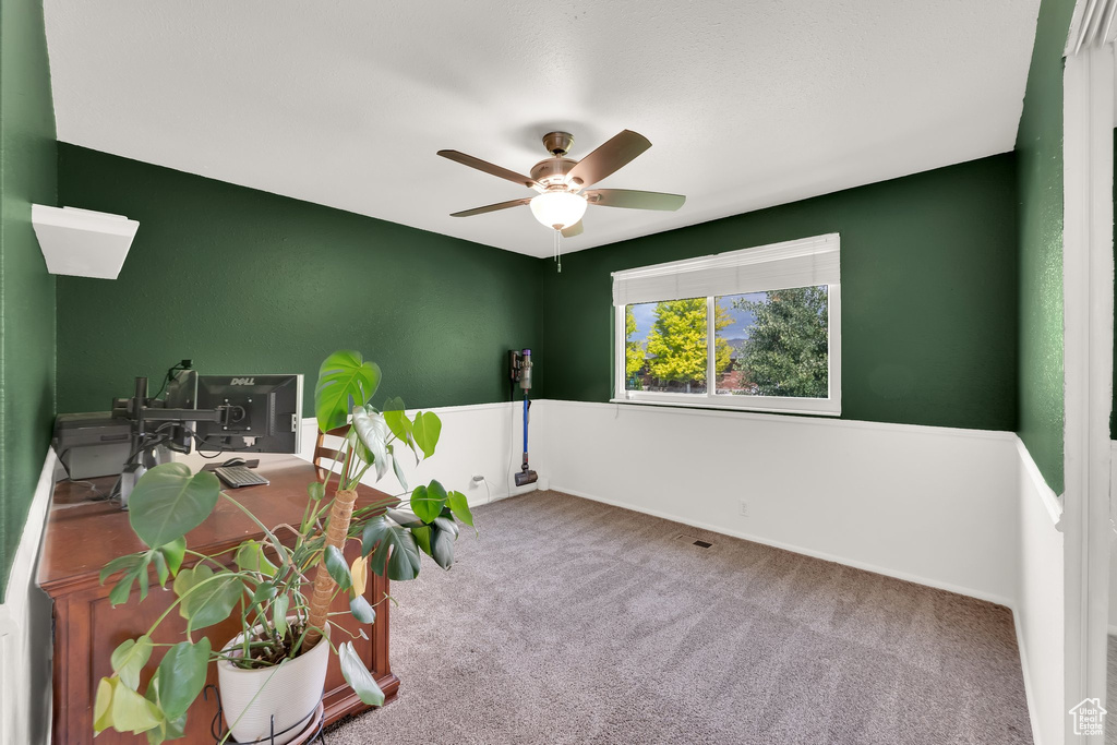 Empty room featuring ceiling fan, carpet flooring, an office area, and baseboards