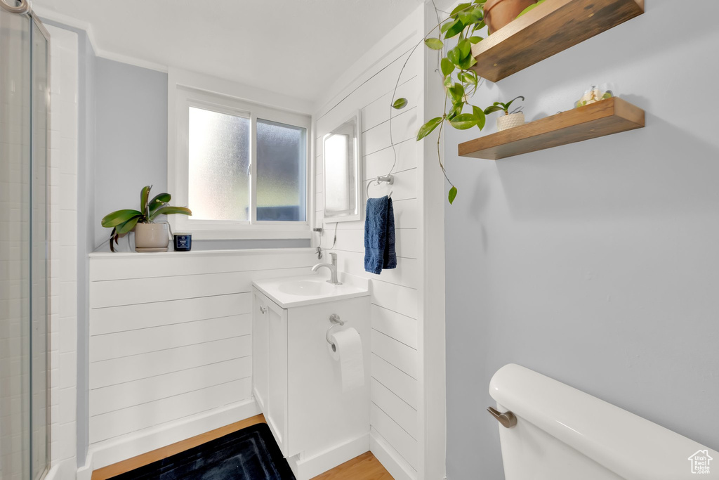 Bathroom with toilet, vanity, a shower with door, and wood finished floors