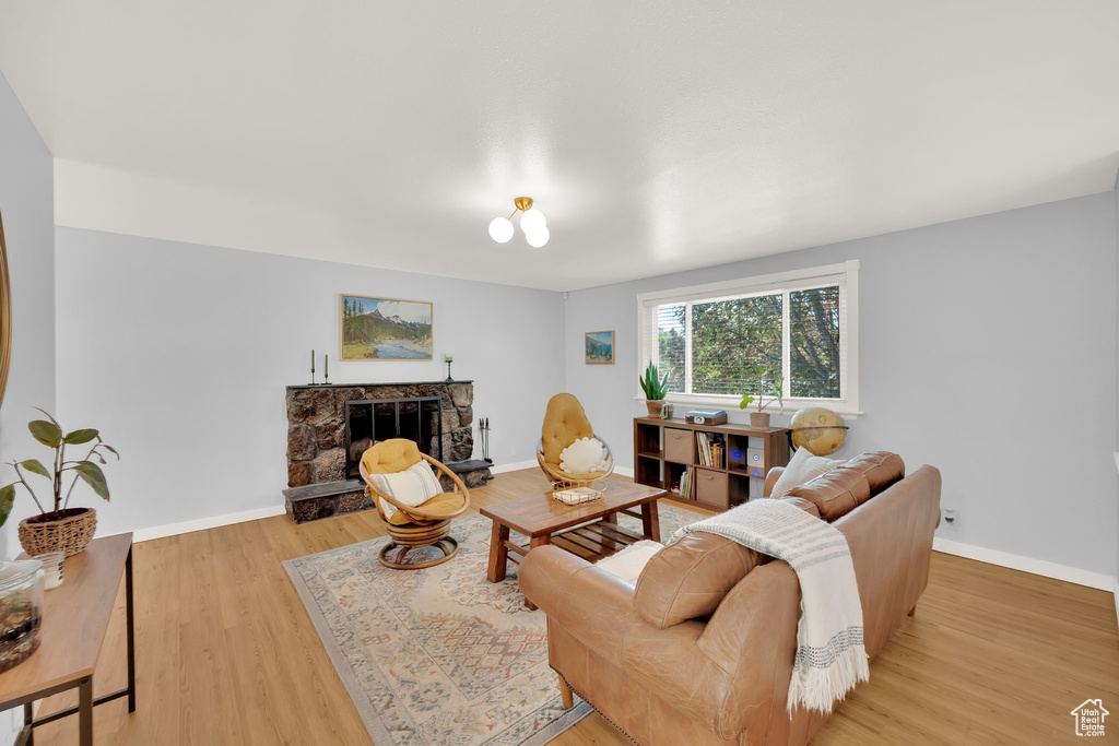 Living area featuring a stone fireplace, light wood finished floors, and baseboards