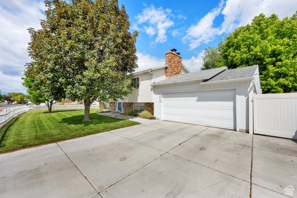 View of front of house with an attached garage, a chimney, driveway, and roof with shingles