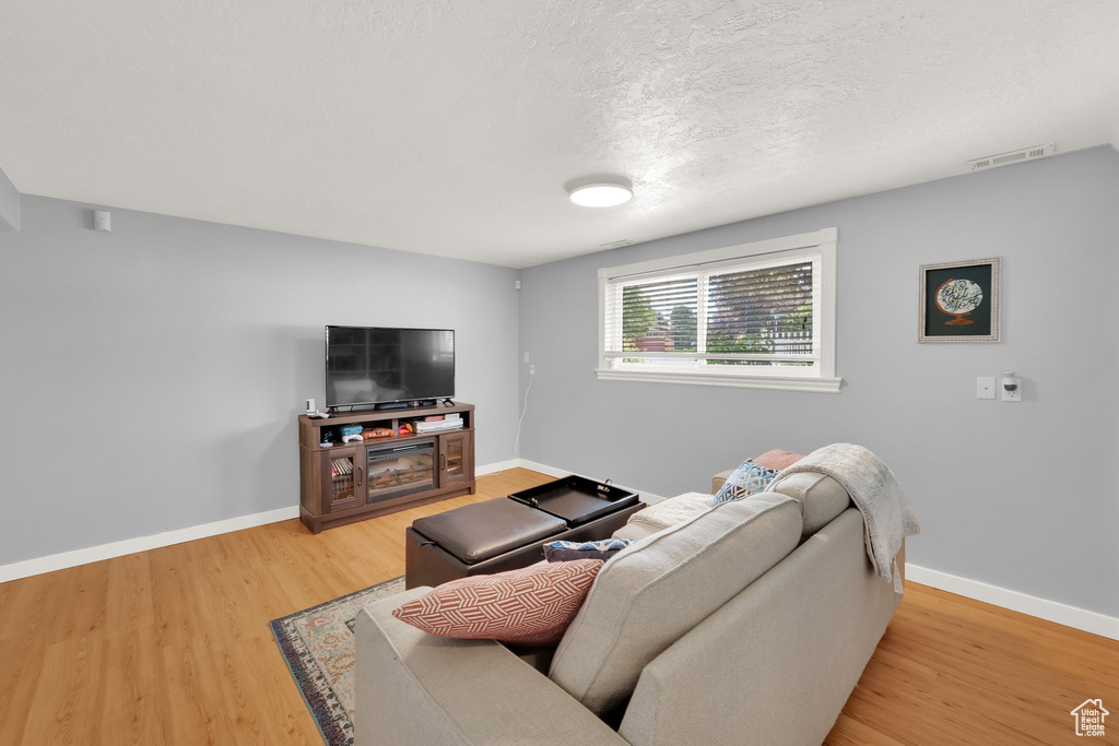 Living area featuring light wood-type flooring, baseboards, and a textured ceiling