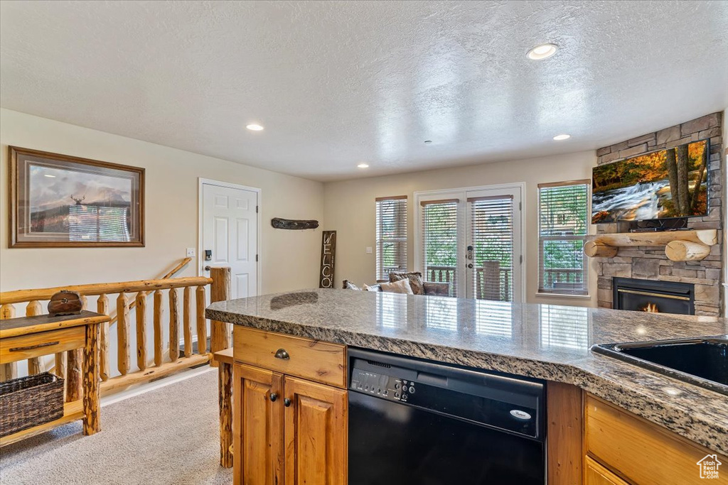 Kitchen with black dishwasher, light carpet, a textured ceiling, a fireplace, and a sink