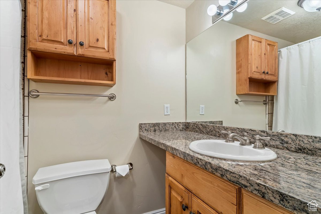 Full bathroom featuring toilet, vanity, and baseboards