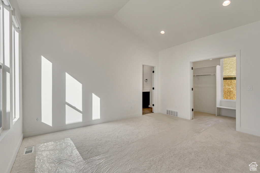 Unfurnished bedroom featuring carpet flooring, recessed lighting, high vaulted ceiling, a spacious closet, and baseboards