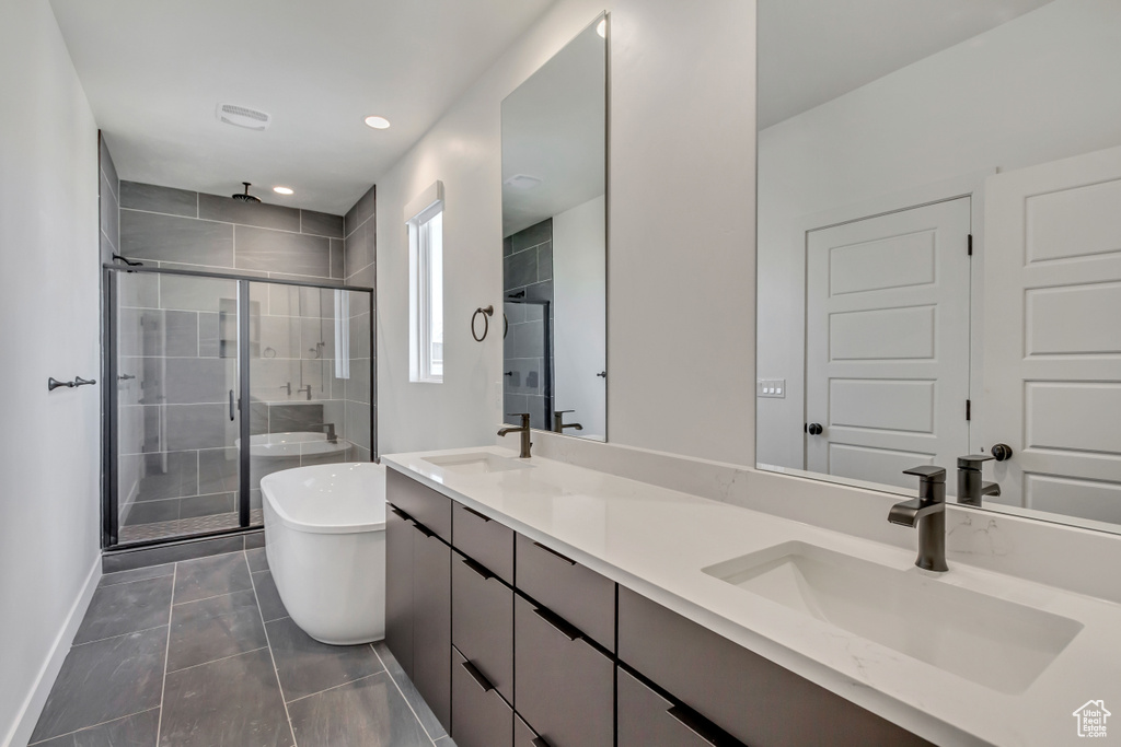 Full bath with a stall shower, double vanity, a soaking tub, baseboards, and recessed lighting