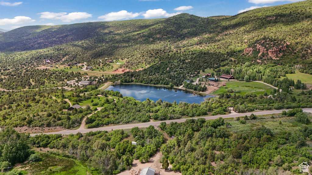 Aerial view of property and surrounding area with a water and mountain view and a forest