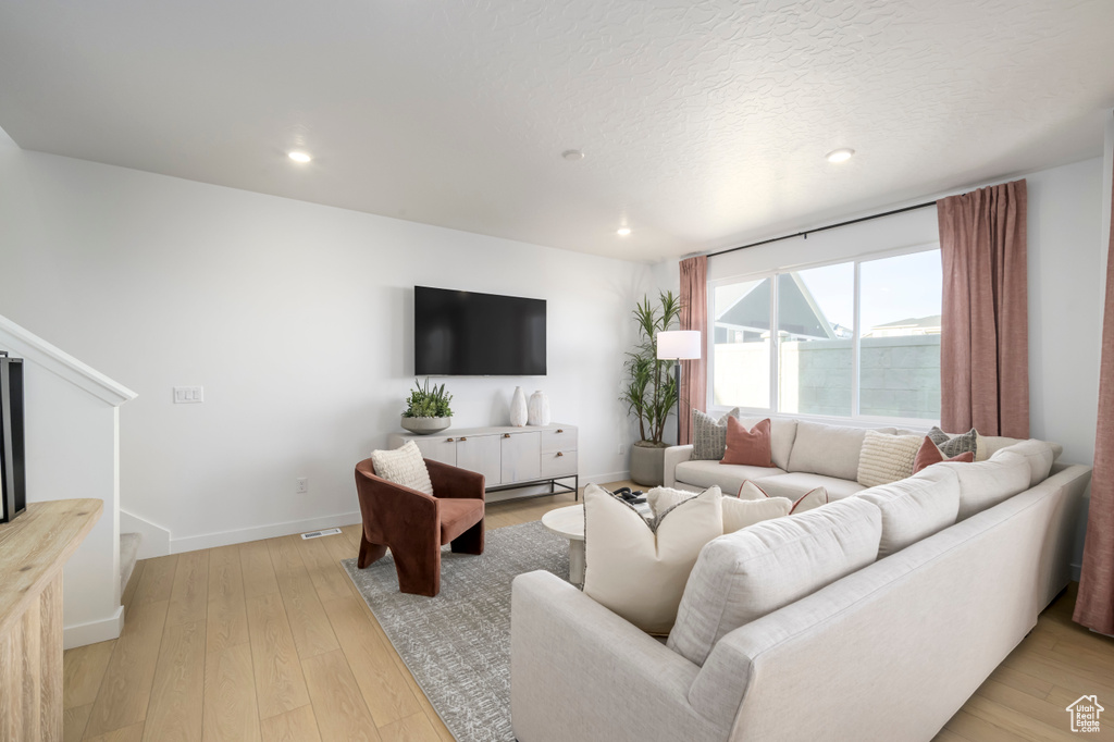 Living area featuring light wood finished floors, recessed lighting, stairway, and baseboards