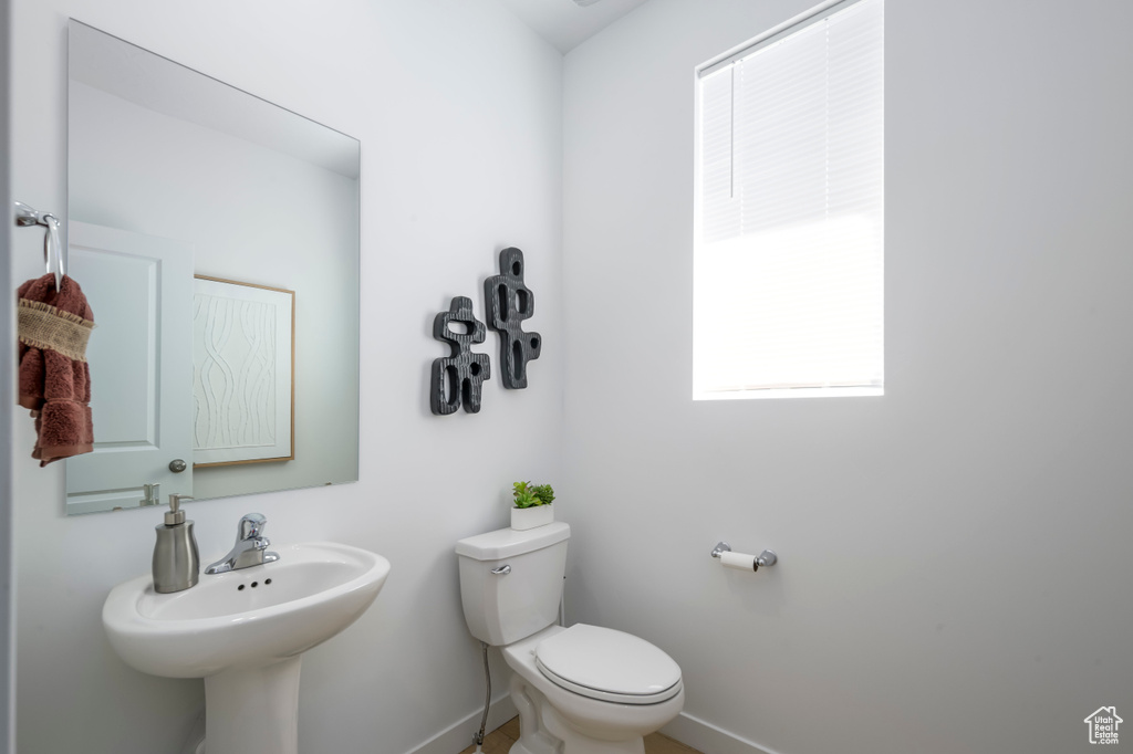 Bathroom featuring baseboards, toilet, and a sink