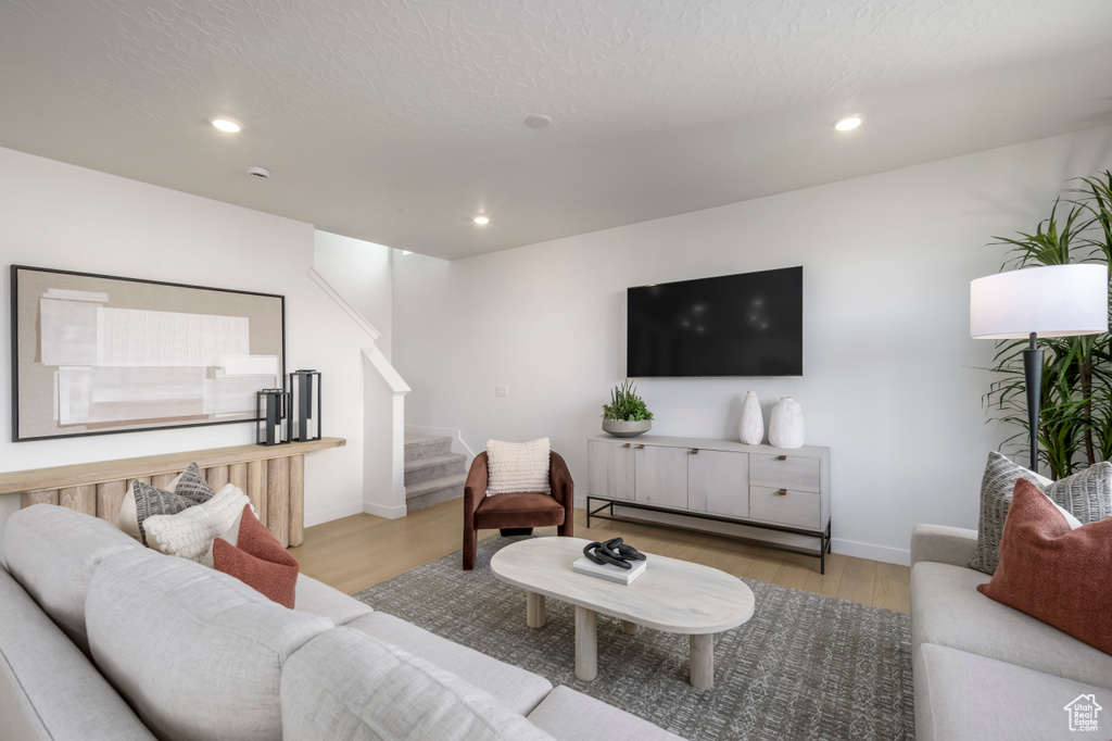 Living room with stairway, wood finished floors, recessed lighting, and baseboards