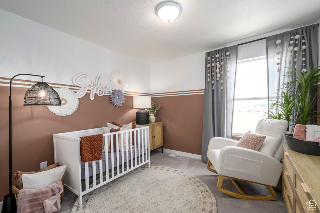 Bedroom with carpet flooring, baseboards, and a crib