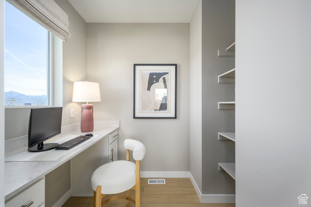 Home office with built in desk, light wood-type flooring, and baseboards
